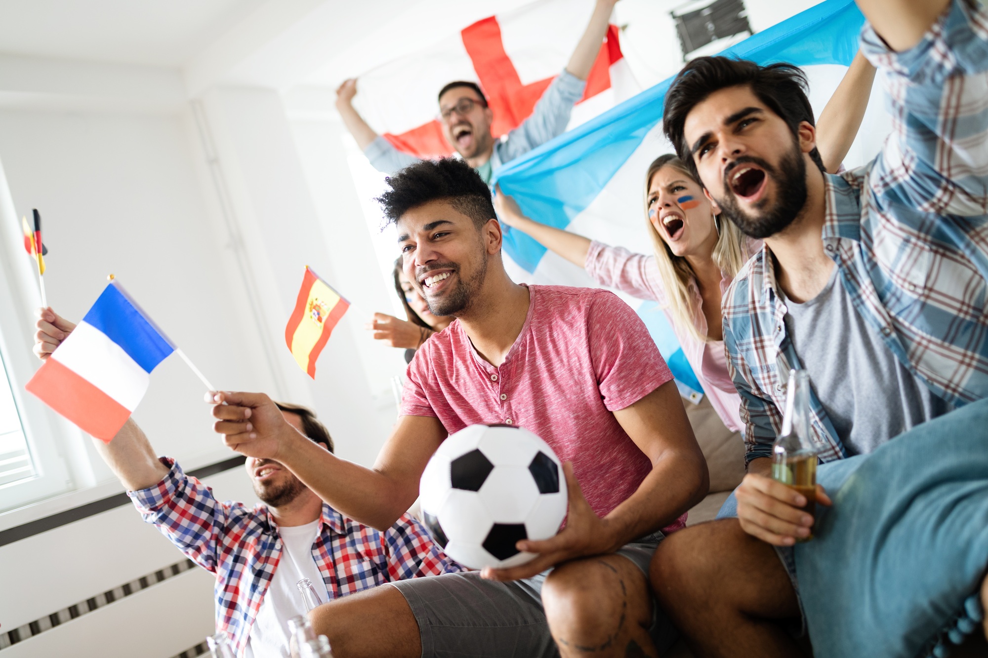 Cheerful and happy group of friends watching olympic games on tv