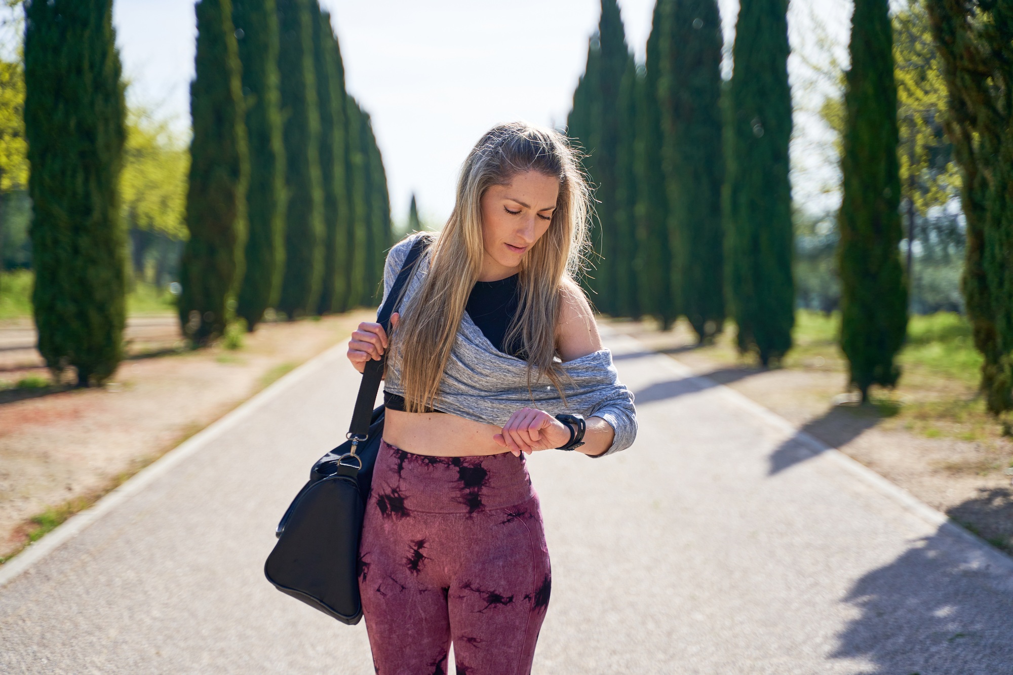 woman walking with a sports backpack looking at her smartwatch